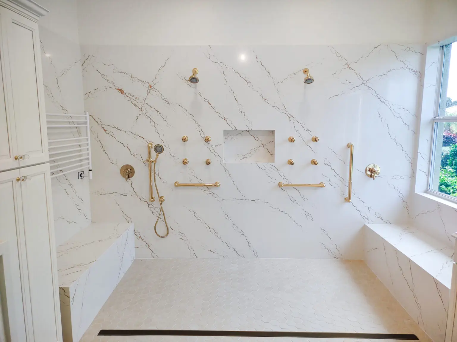 Close-up view of shower walls in a remodeled Venice, Florida master bathroom, showcasing seamless Cambria Inverness Gold quartz installation for a sleek, modern look.