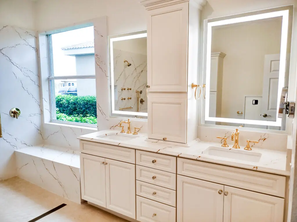 Modern master bathroom remodel in Venice, Florida featuring Cambria Inverness Gold quartz countertops and shower walls, sleek LED mirrors, and a large window letting in natural light.