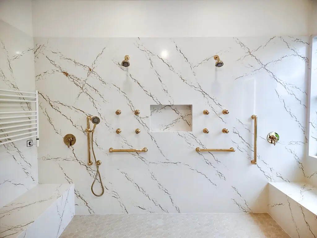 Remodeled master bathroom in Venice, Florida featuring Cambria Inverness Gold quartz on shower walls and vanity countertops. Case study by Kirkplan Kitchen & Bath showcasing seamless quartz installation and modern design.