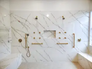 Remodeled master bathroom in Venice, Florida featuring Cambria Inverness Gold quartz on shower walls and vanity countertops. Case study by Kirkplan Kitchen & Bath showcasing seamless quartz installation and modern design.