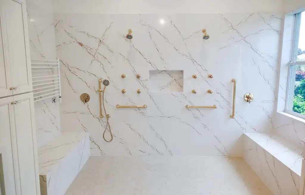 Close-up view of shower walls in a remodeled Venice, Florida master bathroom, showcasing seamless Cambria Inverness Gold quartz installation for a sleek, modern look.